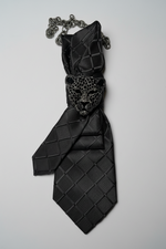 Load image into Gallery viewer, Black patterned tie with decorative panther clasp on a white background.  
