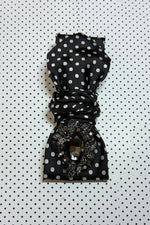 Load image into Gallery viewer, Black polka dot necktie necklace  with decorative brooch on a black and white polka dot background
