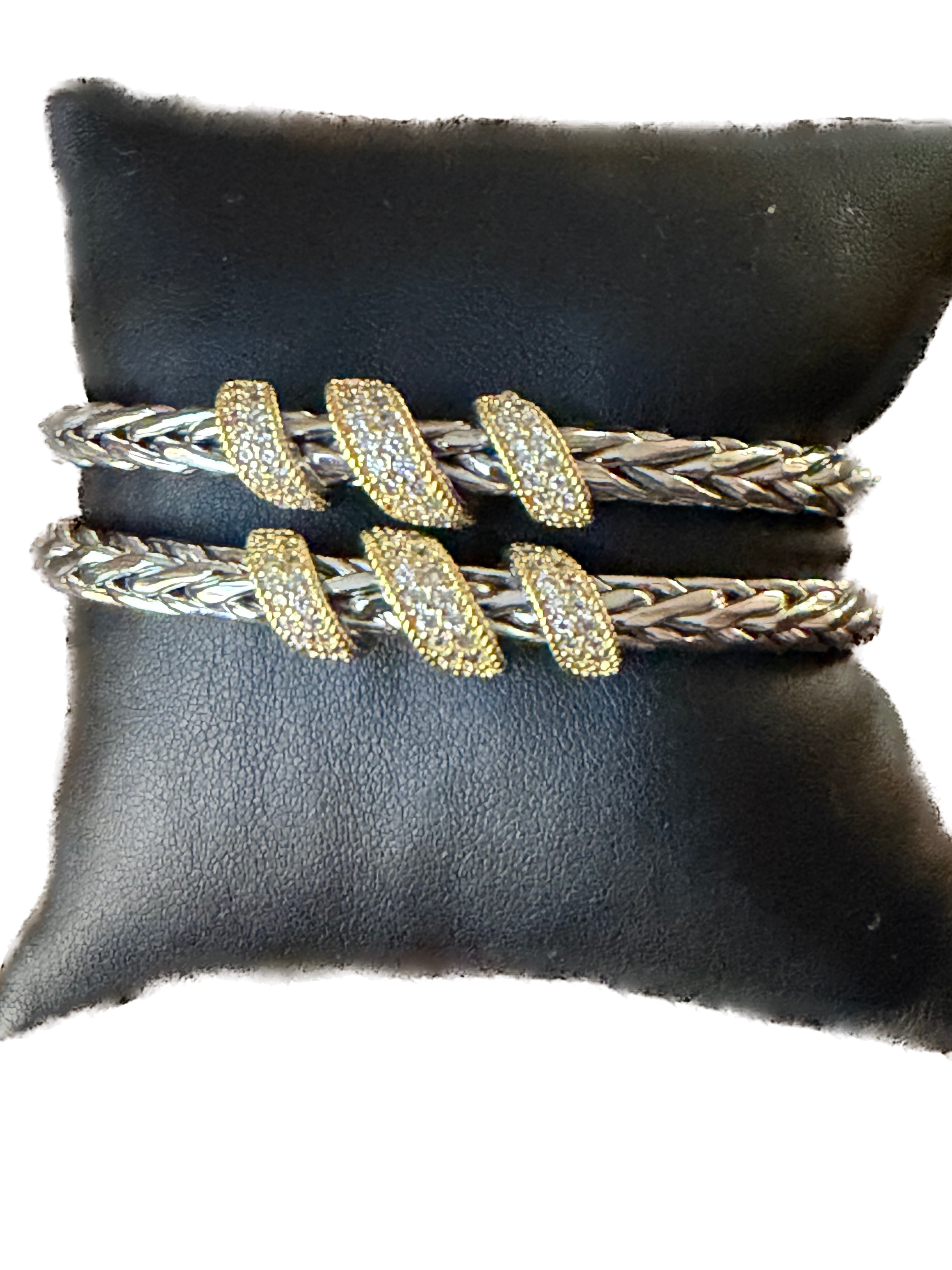 Set of silver and gold bracelets on a black cushion