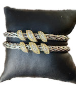 Load image into Gallery viewer, Set of silver and gold bracelets on a black cushion

