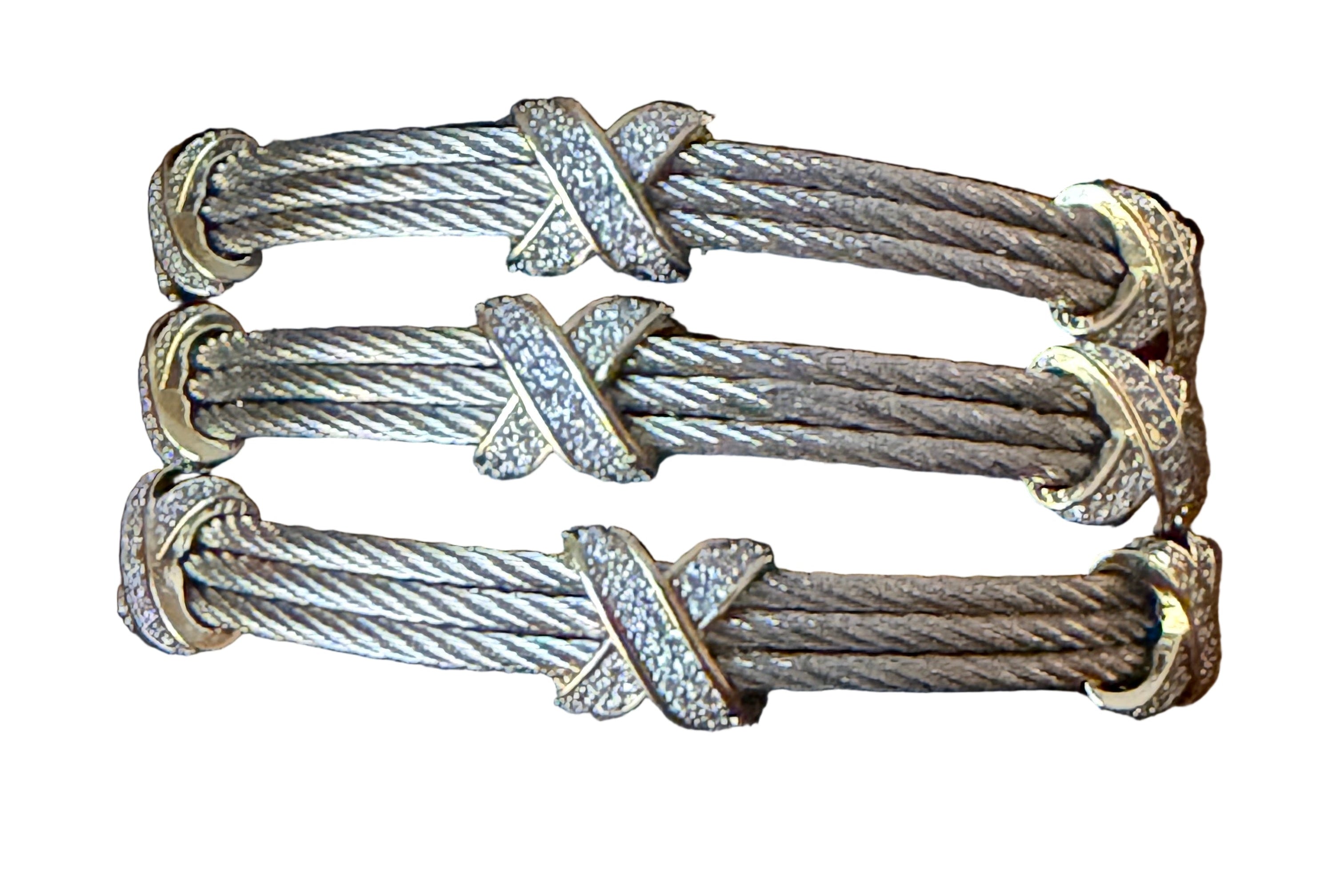 Three silver bracelets with braided design on a dark gray cushion.