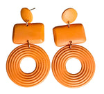 Load image into Gallery viewer, A pair of chunky orange dangle earrings with a small oval stud, a rounded rectangular bar, and a large coiled circular drop, displayed on a white background.
