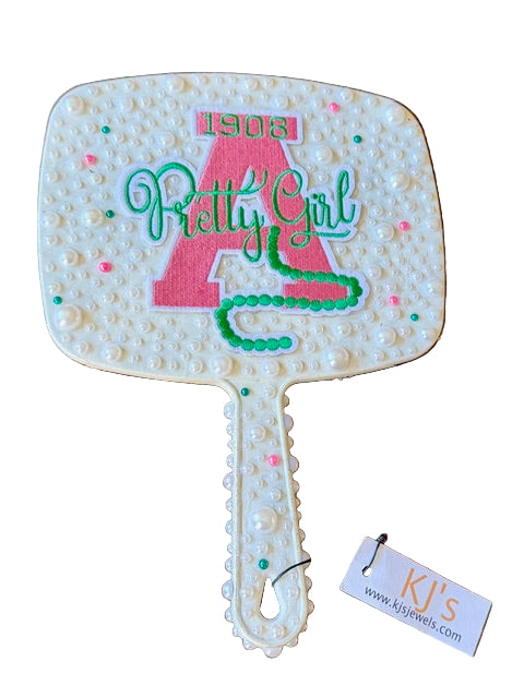 Decorative handheld mirror with '1908 Pretty Girl' text, featuring a tag with 'KJ's' branding.