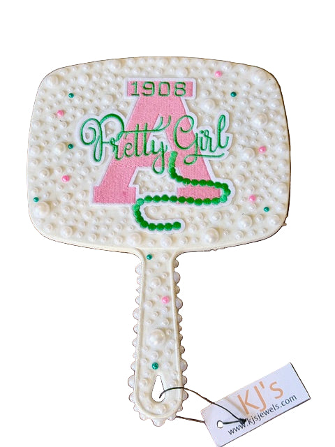 Decorative hand mirror with '1908 Pretty Girl' text  featuring a tag with 'KJ's' branding.