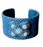 Load image into Gallery viewer, Snakeskin textured cuff bracelet with a decorative clasp on a wooden surface
