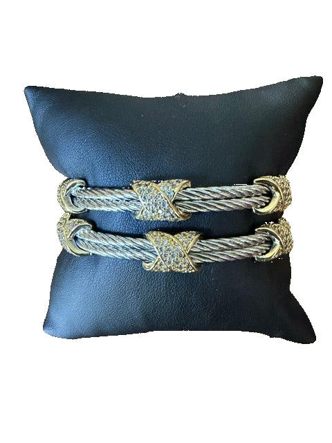 Pair of gold and silver bracelets on a black cushion 