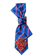 Load image into Gallery viewer, Blue tie with red stripes and decorative brooch  on a white surface
