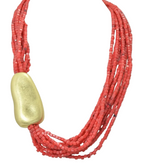 Load image into Gallery viewer, A multi-strand red beaded necklace with a large, smooth, matte gold pendant, displayed on a clean white background.
