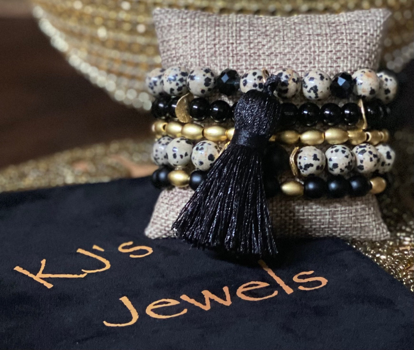 5 stretch bracelets with round Dalmatian jasper beads, gold barrel beads and round onyx beads; black knit tassel accent 